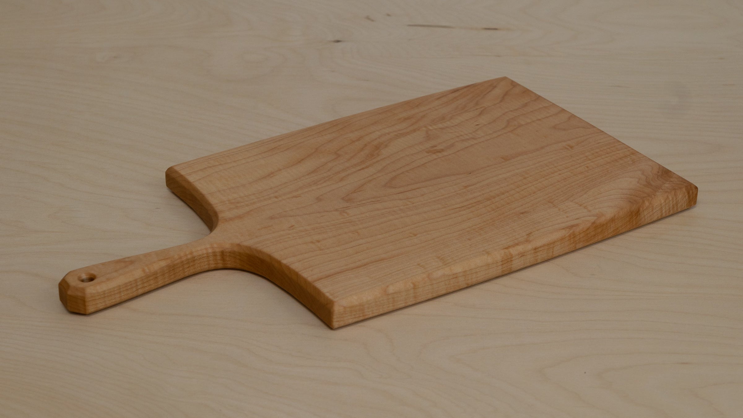 Wooden serving board with a handle on a wooden surface