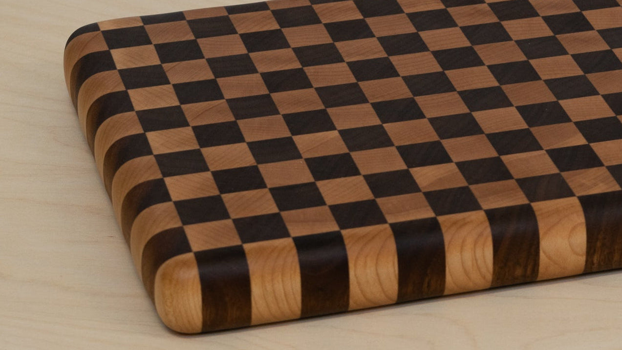Checkered wooden cutting board on a light wood surface