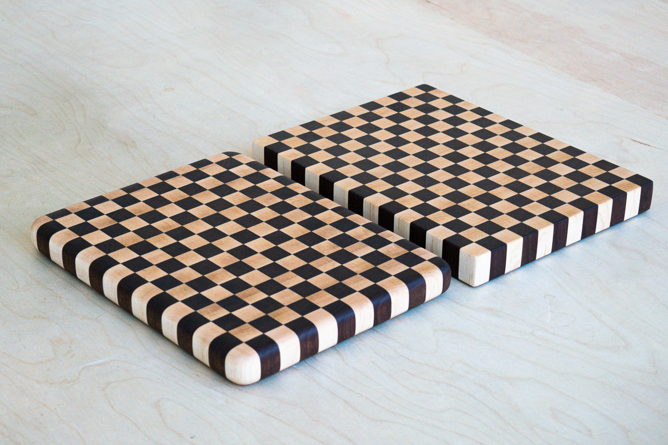 Two checkered wooden cutting boards on a light wooden surface