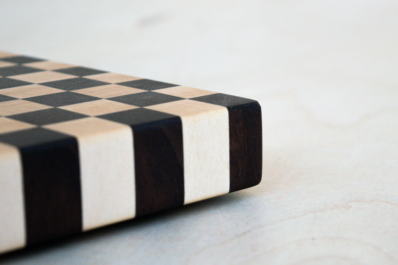 Close-up of a black and white checkered cutting board on a light surface.