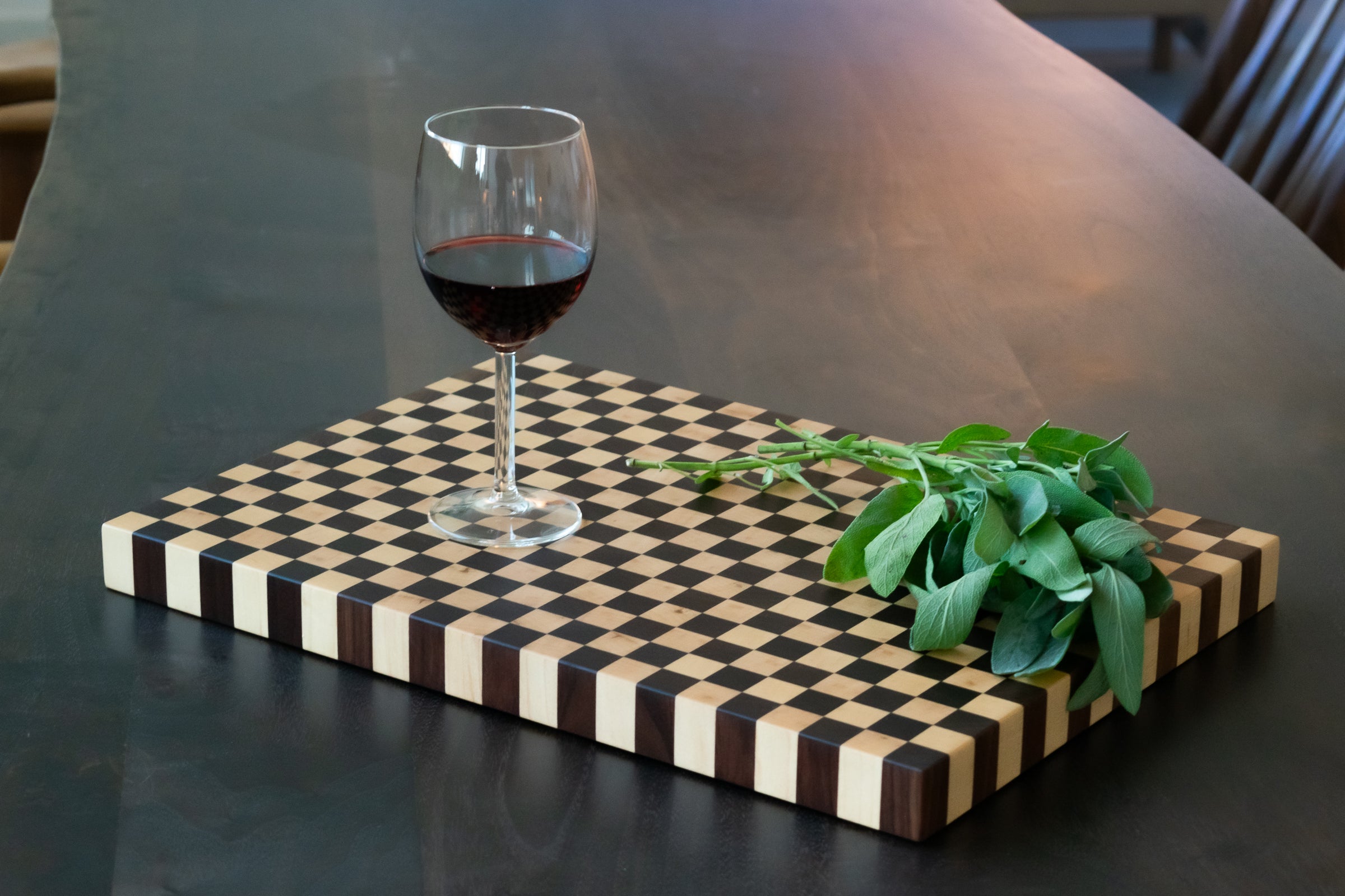 wine glass and sage on a checkerboard cutting board on a table